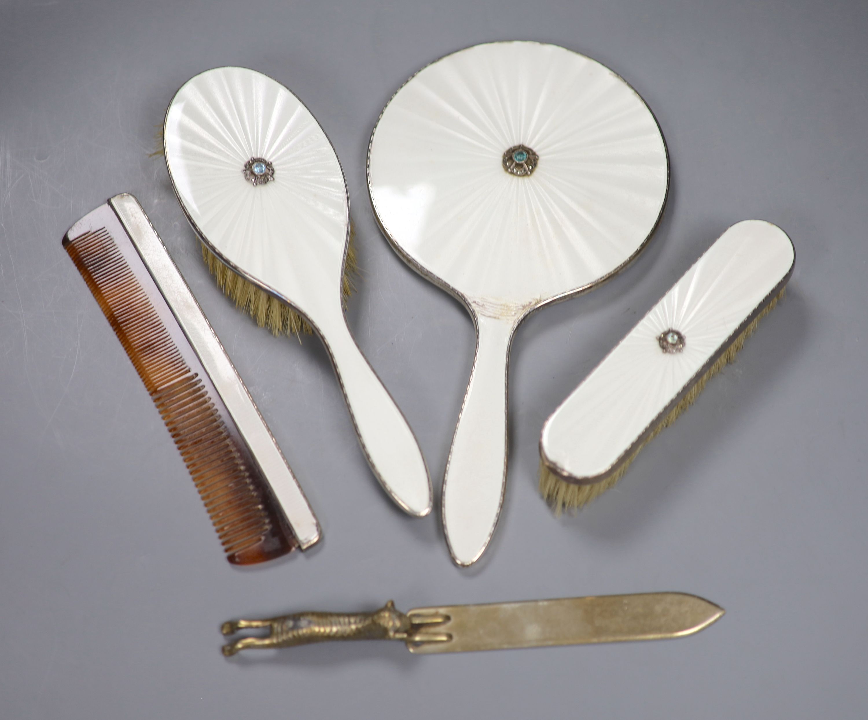 A four piece silver and enamel dressing table set and a brass page turner